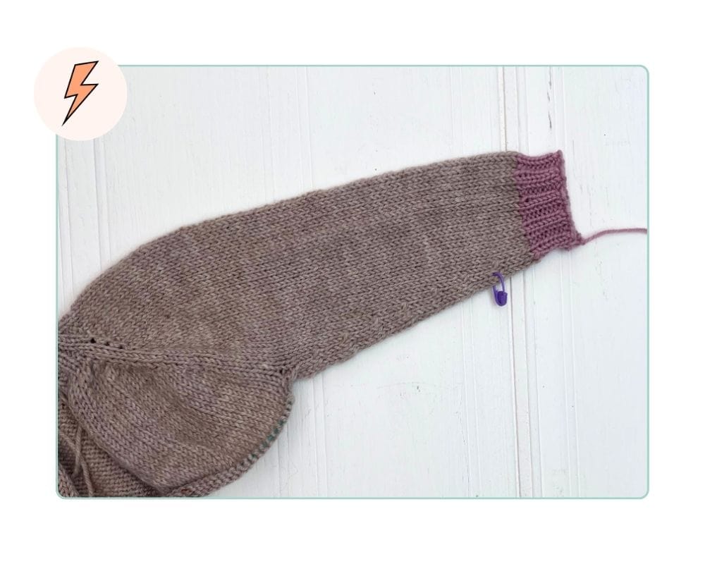 Image shows, completed cuff ribbing in contrast colour on a top-down seamless children's cardigan sleeve