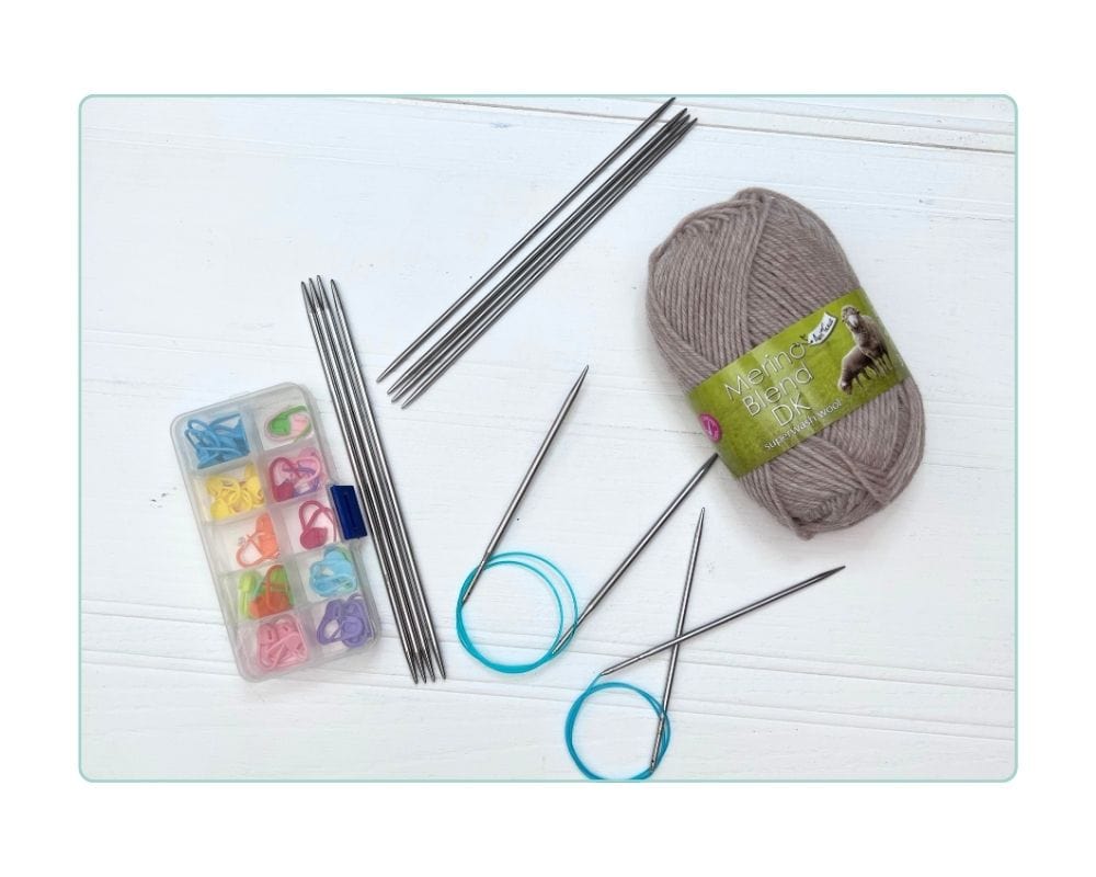 Supplies for top down cardigan knitting for kids, including circular needles, stitch markers, DK yarn, and scrap yarn how-to-knit-a-top-down-cardigan-for-kids