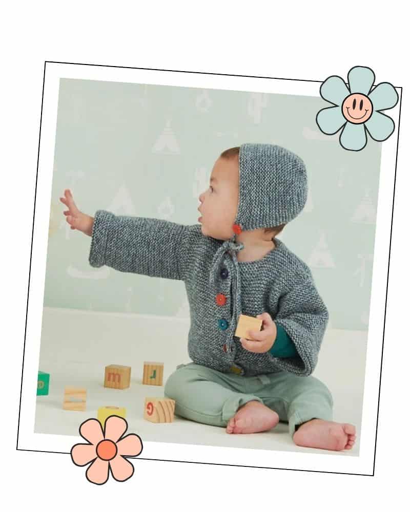 Baby reaching out while wearing the garter stitch baby bonnet, photo in a decorative frame