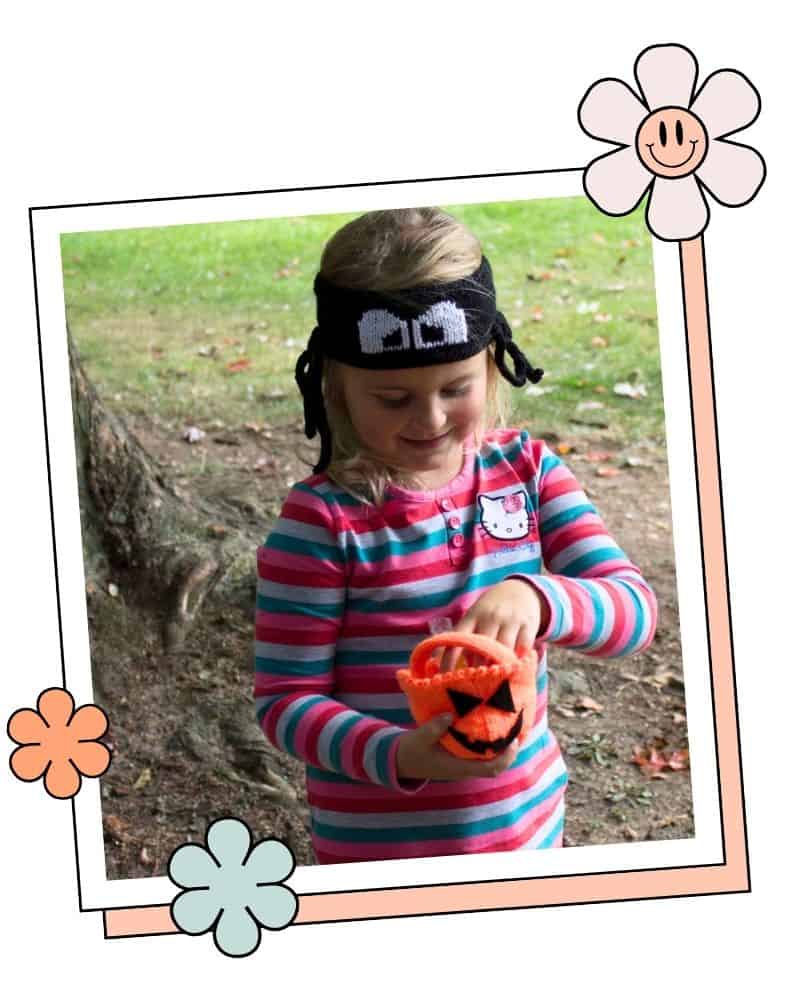 trick or treat pumpkin bag knitting pattern, young girl holding orange knitted pumpkin bag outdoors